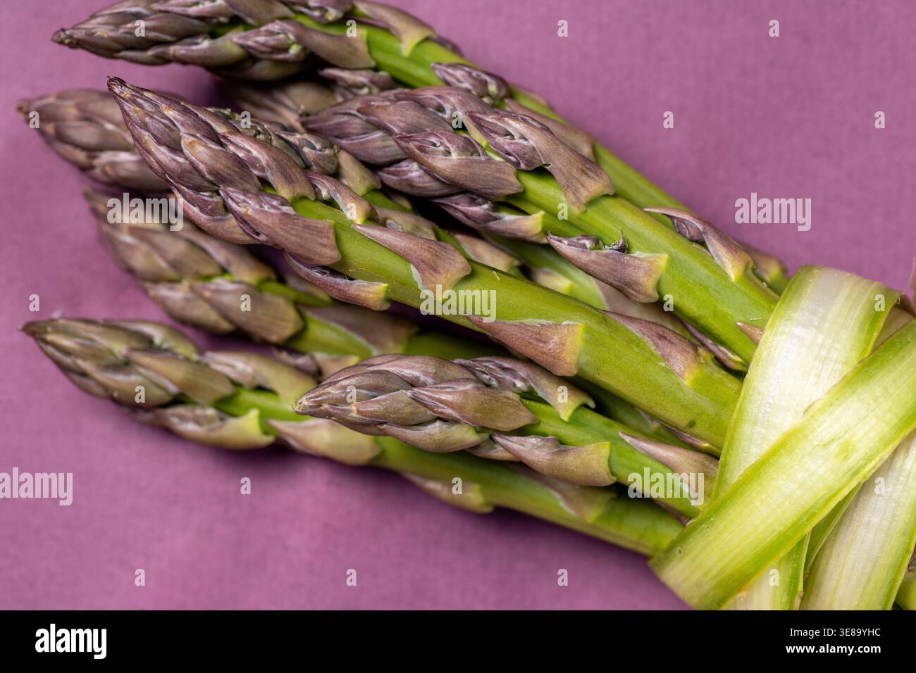 Faisceau d'asperges liées ensemble sur une surface violette. Banque D'Images
