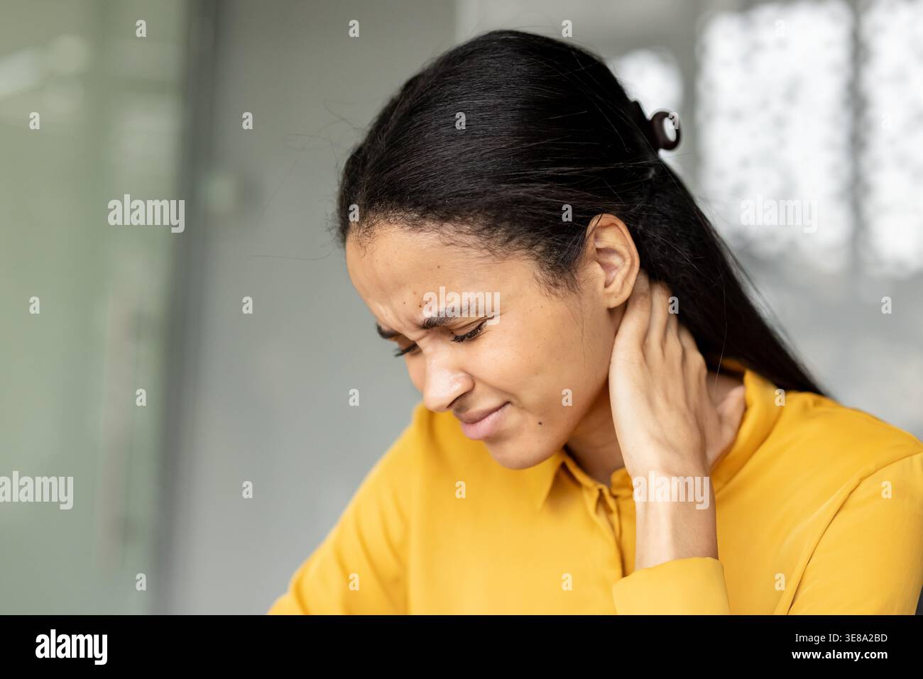 Femme debout souffrant de douleurs sévères au cou, massant ses muscles tendus en raison de l'inconfort, du stress, de la raideur et de l'épuisement, indiquant un problème de santé Banque D'Images