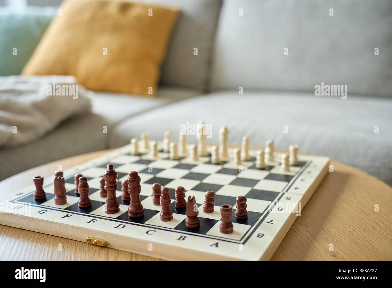 Échiquier en bois avec des pièces disposées sur la table prête à jouer dans l'intérieur du salon. Concept de stratégie, de logique, d'activité de loisirs et de jeu intellectuel. Banque D'Images
