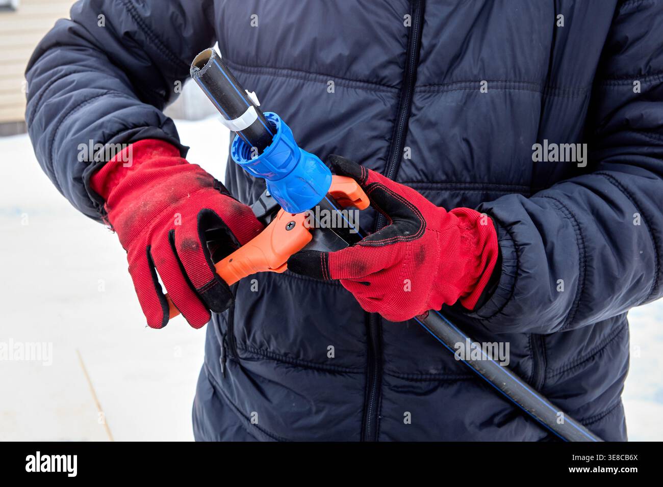 Utilisation d'un coupe-tube à cliquet pour travailler avec des tuyaux en PEHD. Banque D'Images