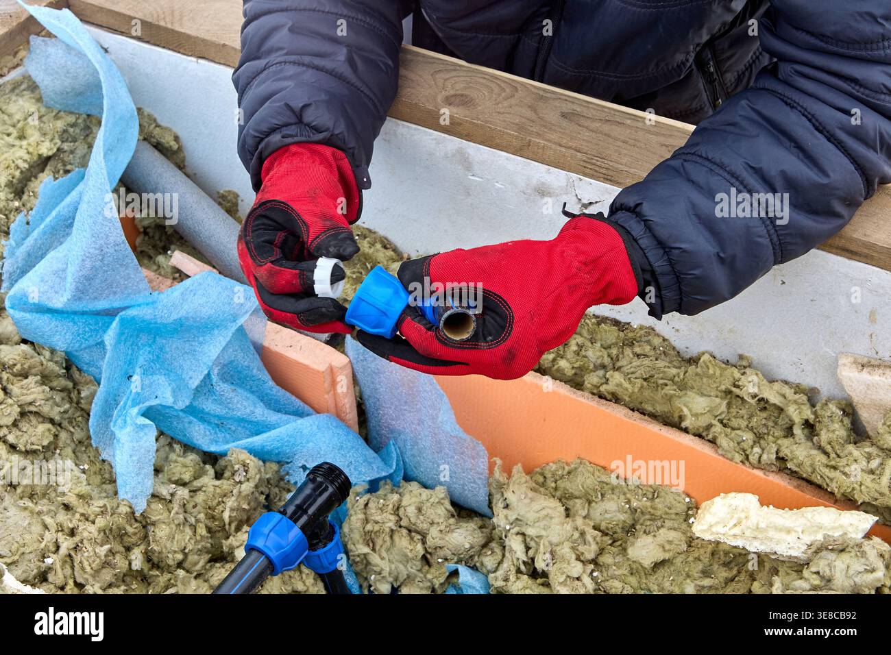 Plombier insérant le segment de compression dans l'écrou de compression pendant la réparation de la tuyauterie de distribution PEHD dans la fosse de puits. Banque D'Images