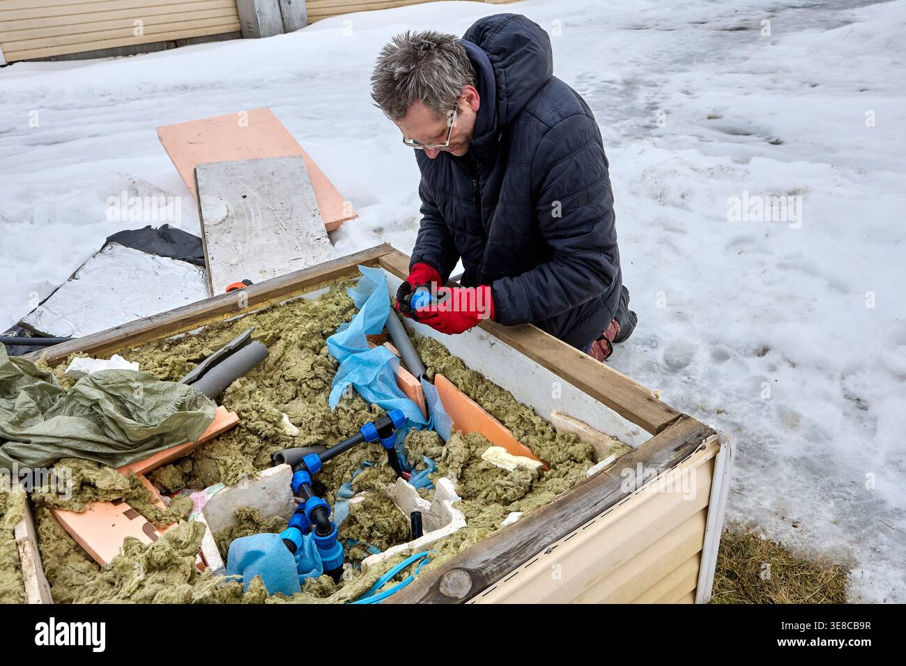 Raccord de compression en plastique pour tuyaux en PEHD dans les mains du propriétaire installant la tuyauterie de distribution dans la fosse de puits artésienne. Banque D'Images