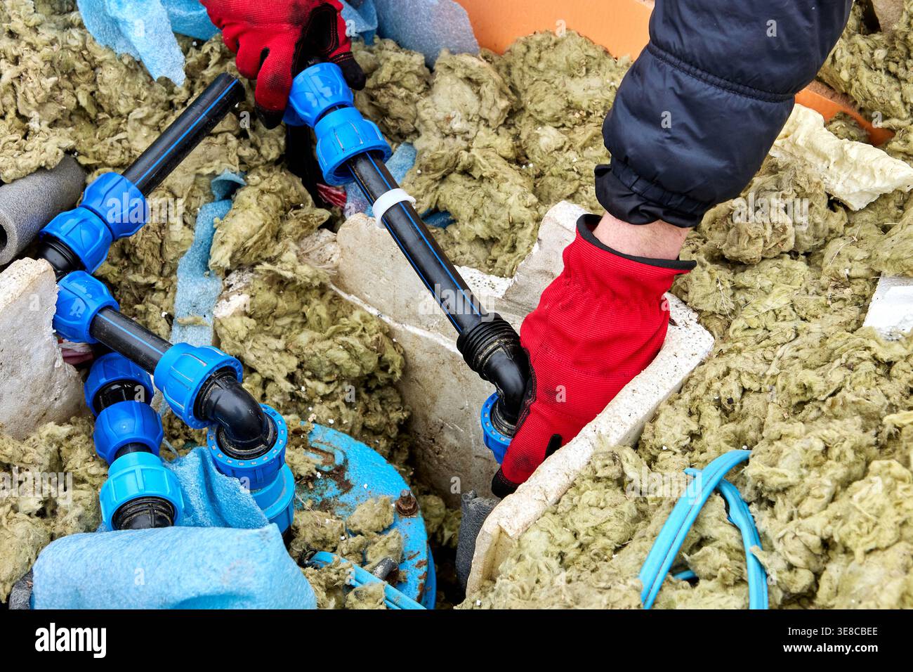 Raccord de compression en main du plombier réparant la fosse de puits. Banque D'Images