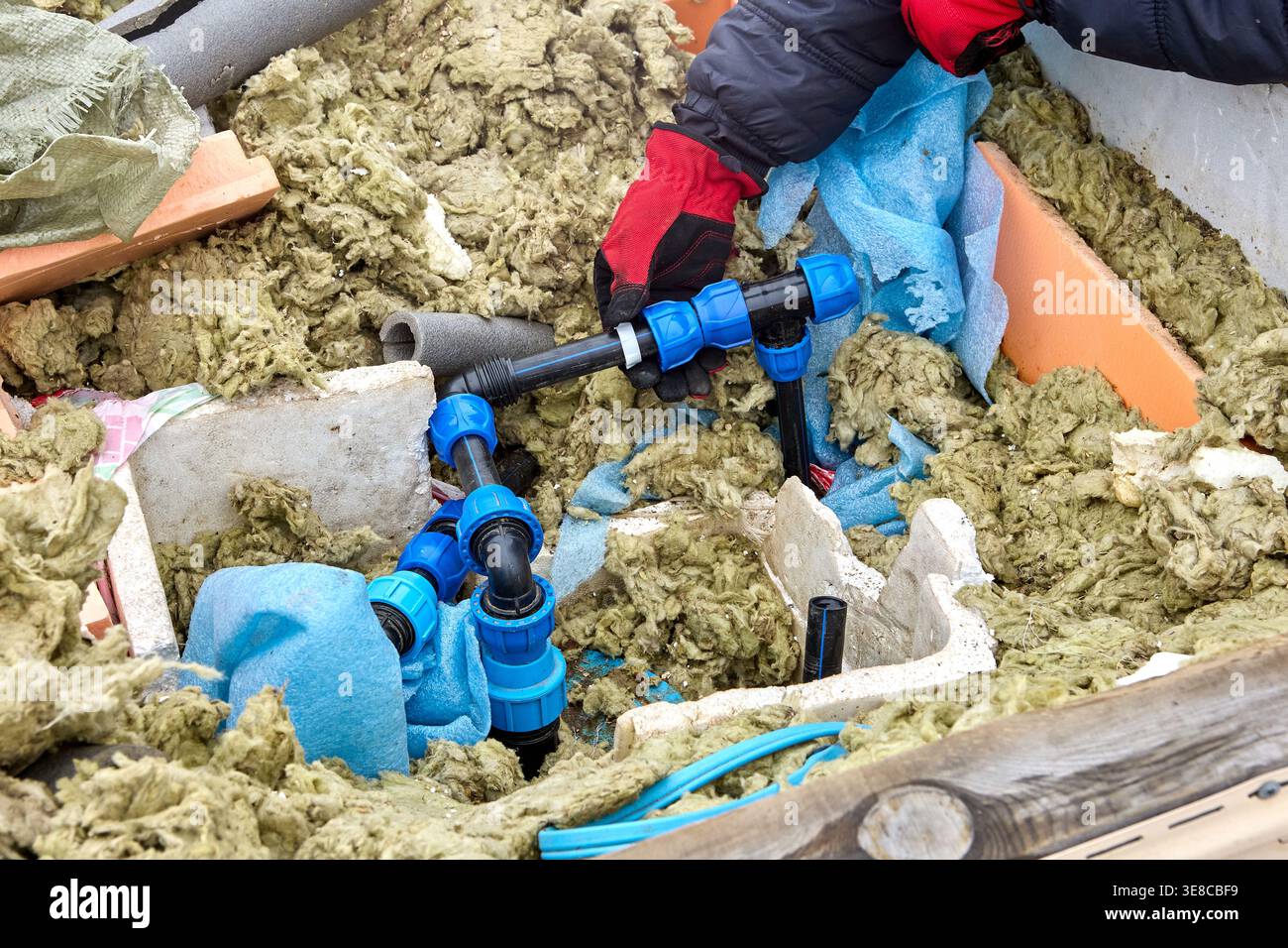 Utilisation de raccords de compression en plastique pour tuyaux en PEHD lors de l'installation de tuyauterie de distribution dans une fosse de puits artésienne. Banque D'Images