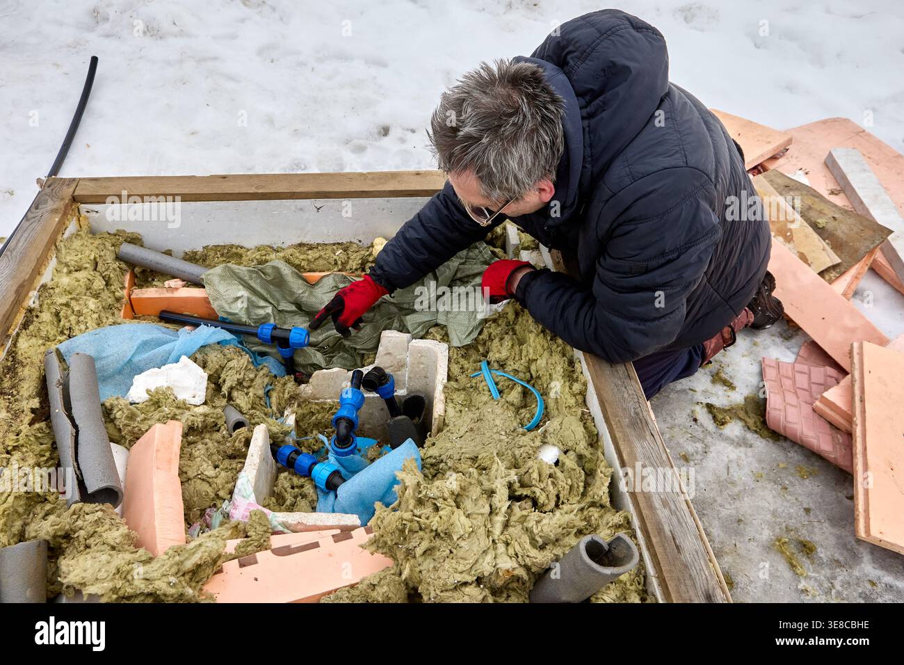 Plombier installant la tuyauterie de distribution de puits en hiver dans une région rurale enneigée. Banque D'Images