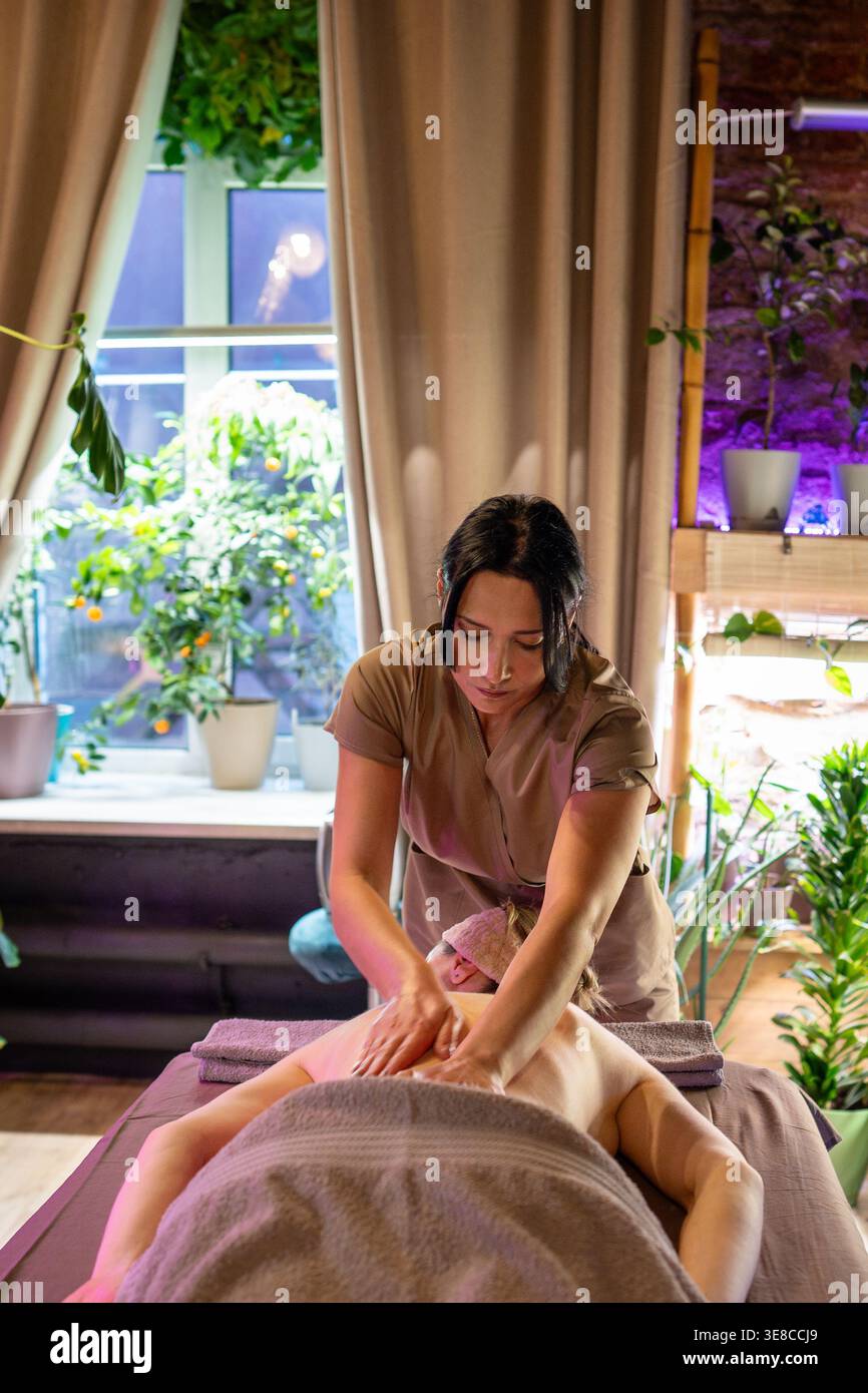 Masseuse professionnelle de dame faisant massage complet de guérison pour la femme cliente dans le salon de spa. Banque D'Images