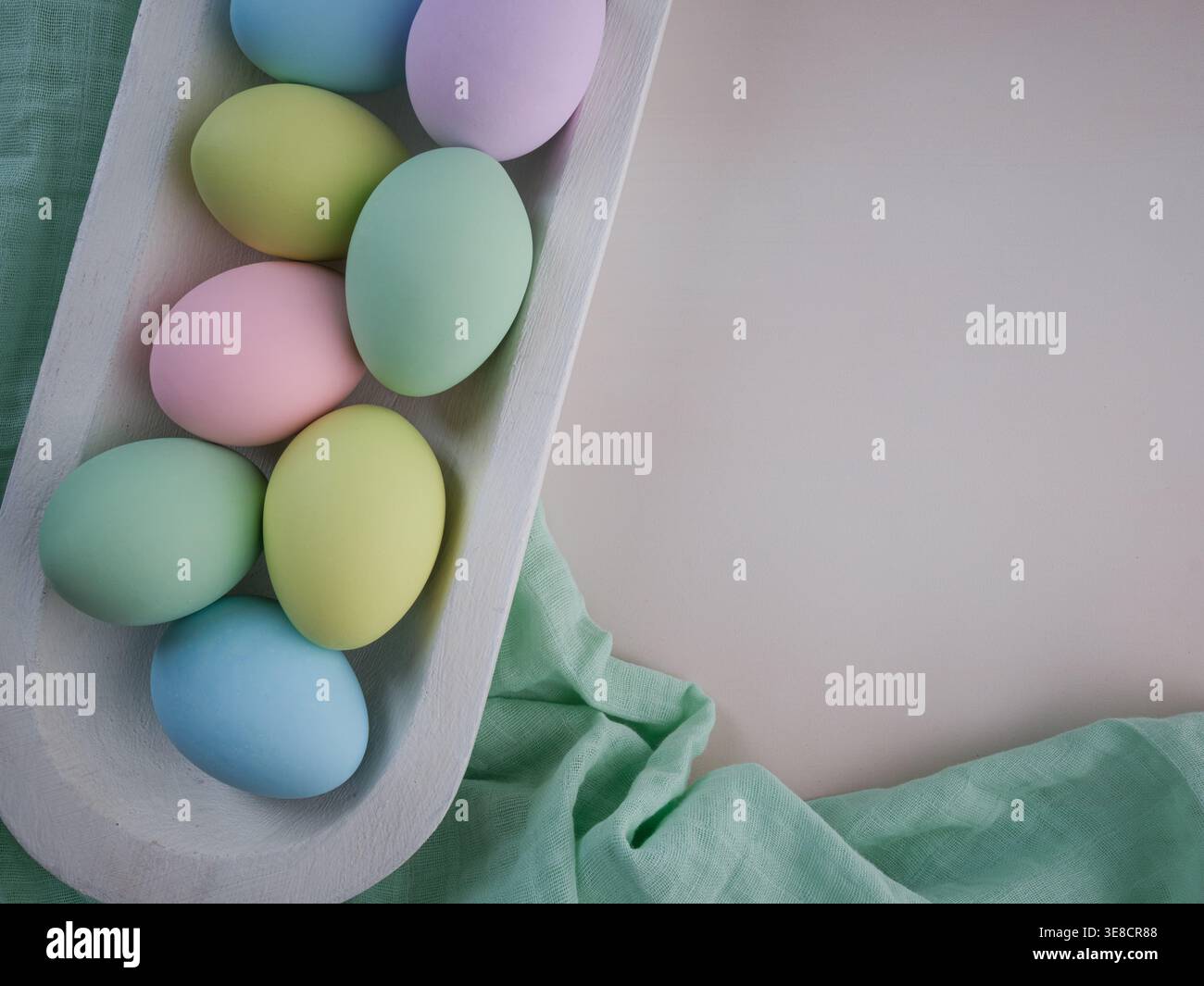 Oeufs de Pâques pastel colorés dans un plateau de bol rustique de ferme en bois blanc sur tissu de mousseline verte. Fond de carte de décor de printemps Banque D'Images