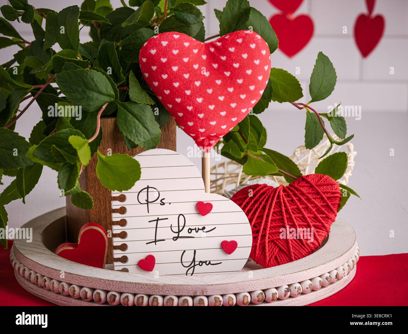 Rouge et blanc 14 février décor de la Saint-Valentin. Plateau rustique avec signe romantique et PS I LOVE YOU texte, cœurs de fil, verdure et cœur doux Banque D'Images