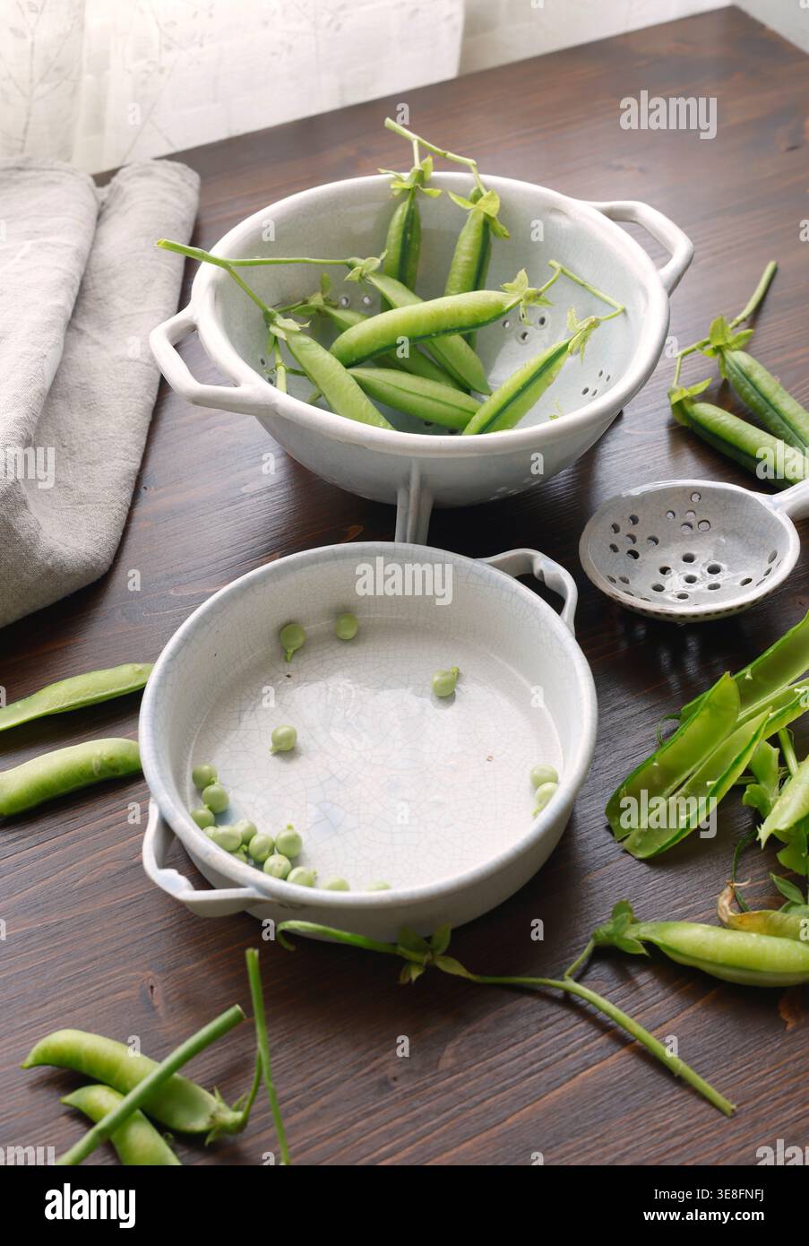 Pois verts biologiques frais décortiqués dans des bols en céramique sur une table en bois sombre avec espace de copie. Le tir à angle élevé comprend des gousses de pois et des pois individuels Banque D'Images