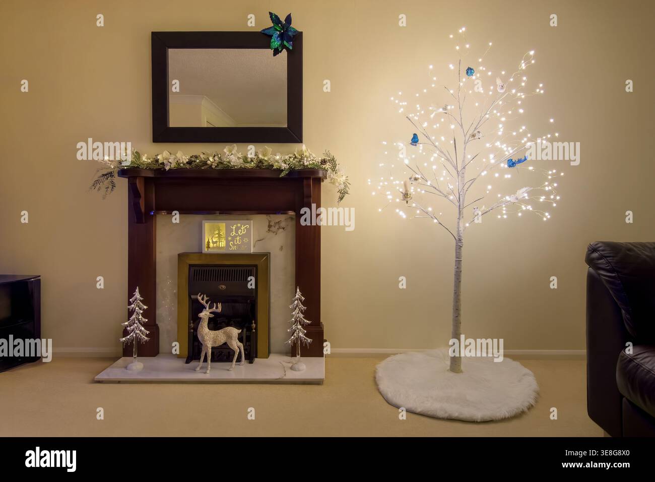 Salon de Noël minimaliste avec arbre décoratif éclairé, cheminée et décorations festives dans un intérieur calme et moderne Banque D'Images