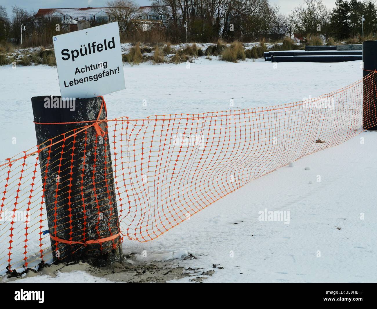 Clôture de sécurité en plastique orange sur la neige avec fort contraste de couleur et motif de filet graphique. Copyspac Banque D'Images