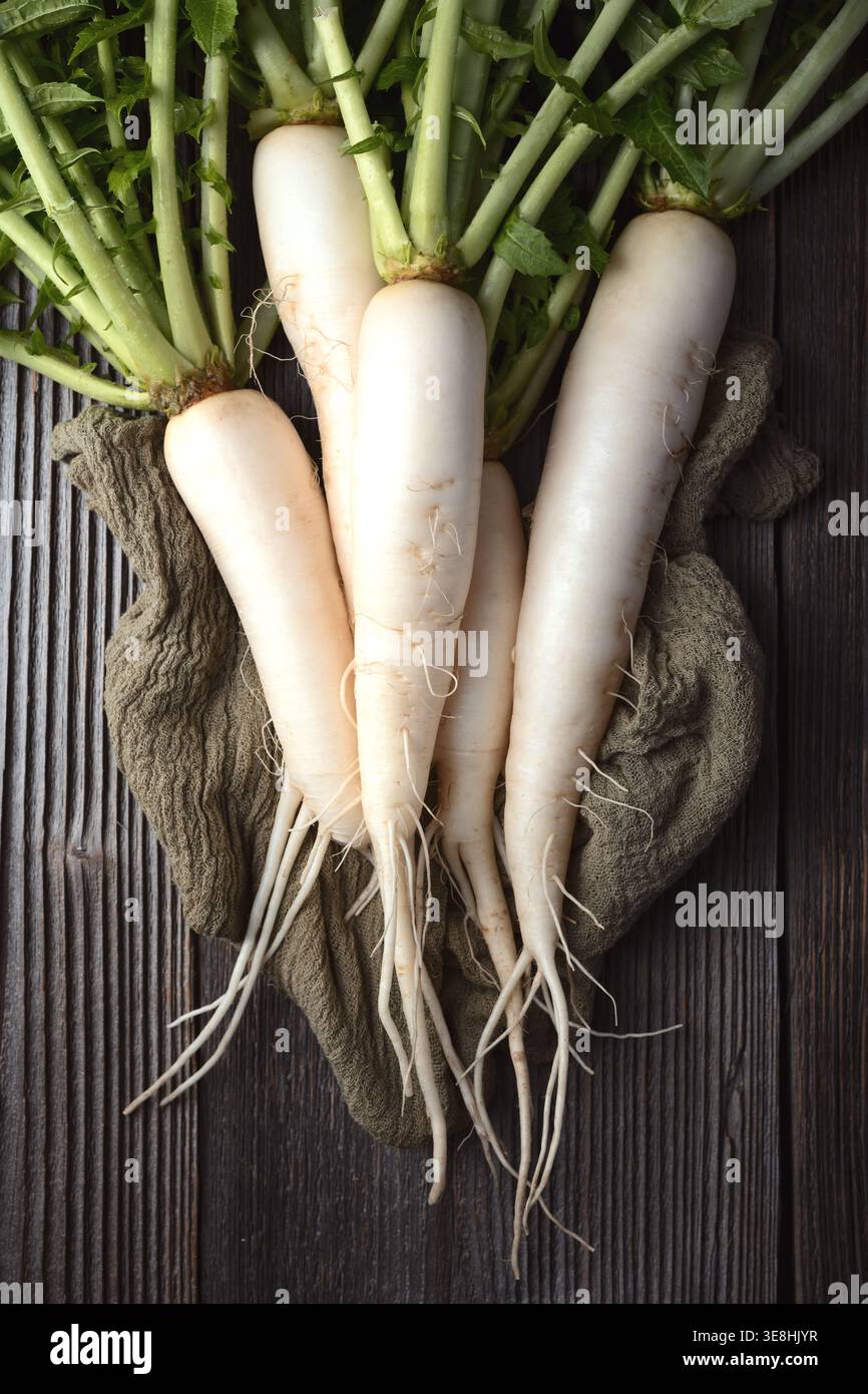 Radis daikon avec de longues racines sur fond de bois texturé, radis blanc, légumes frais de ferme Banque D'Images