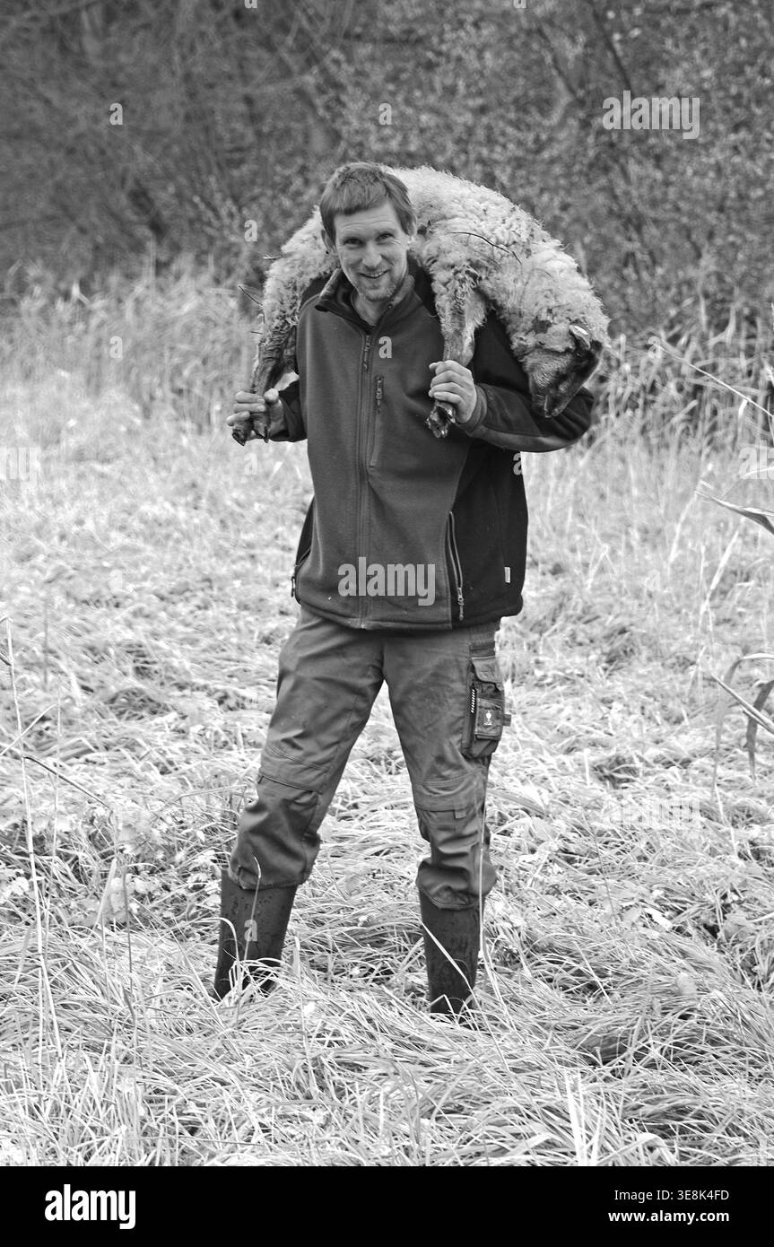 Jeune berger portant un jeune mouton sur ses épaules, noir et blanc, Pinnow, Mdecklenburg-Poméranie occidentale, Allemagne Banque D'Images