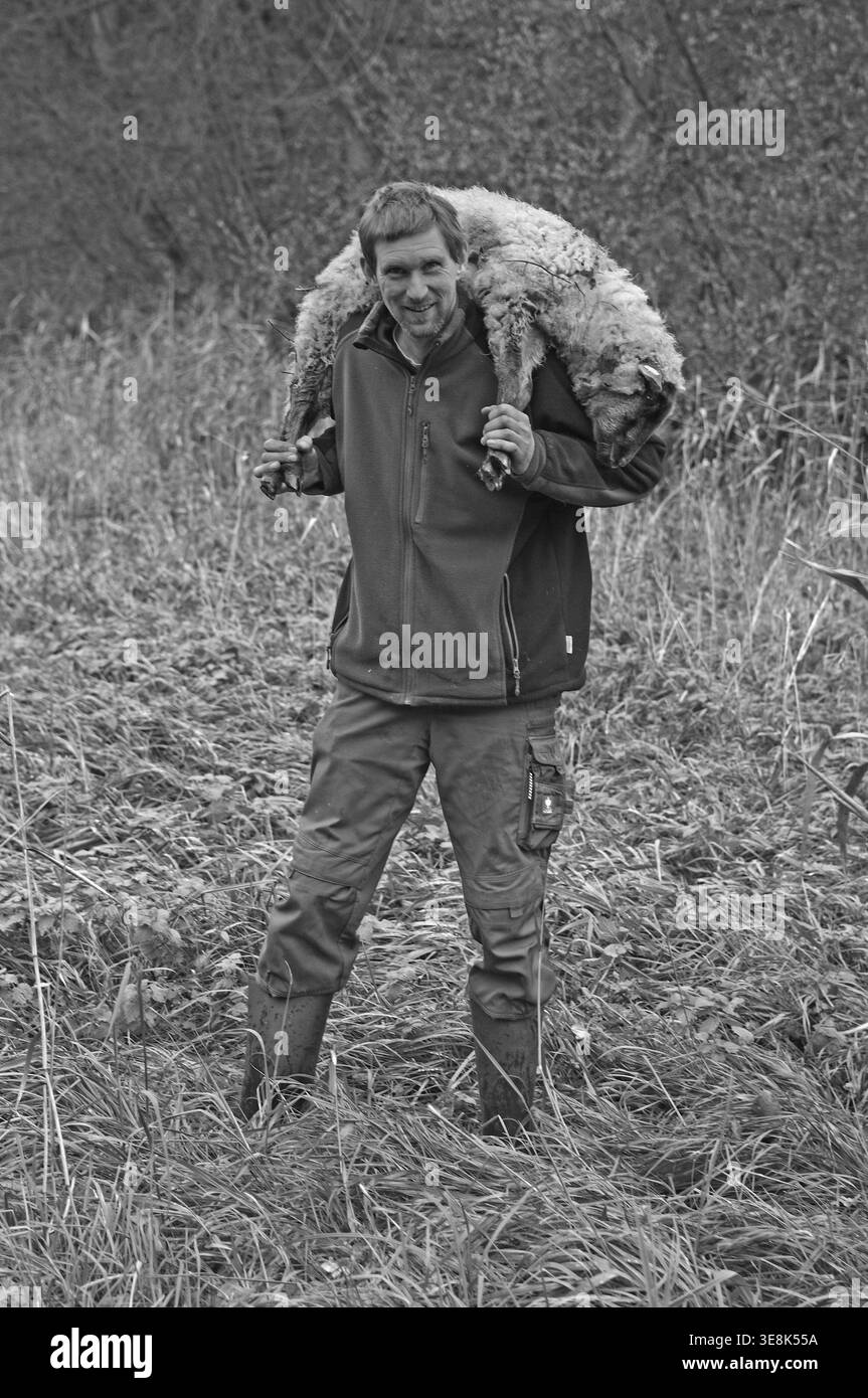Jeune berger portant un mouton faible sur ses épaules, noir et blanc, Pinnow, Mecklembourg-Poméranie occidentale, Allemagne Banque D'Images