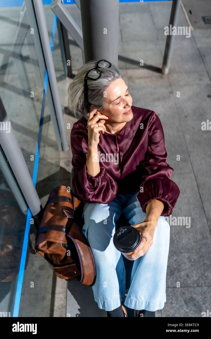 Femme profitant de la pause café dans la lumière du soleil de la ville Banque D'Images