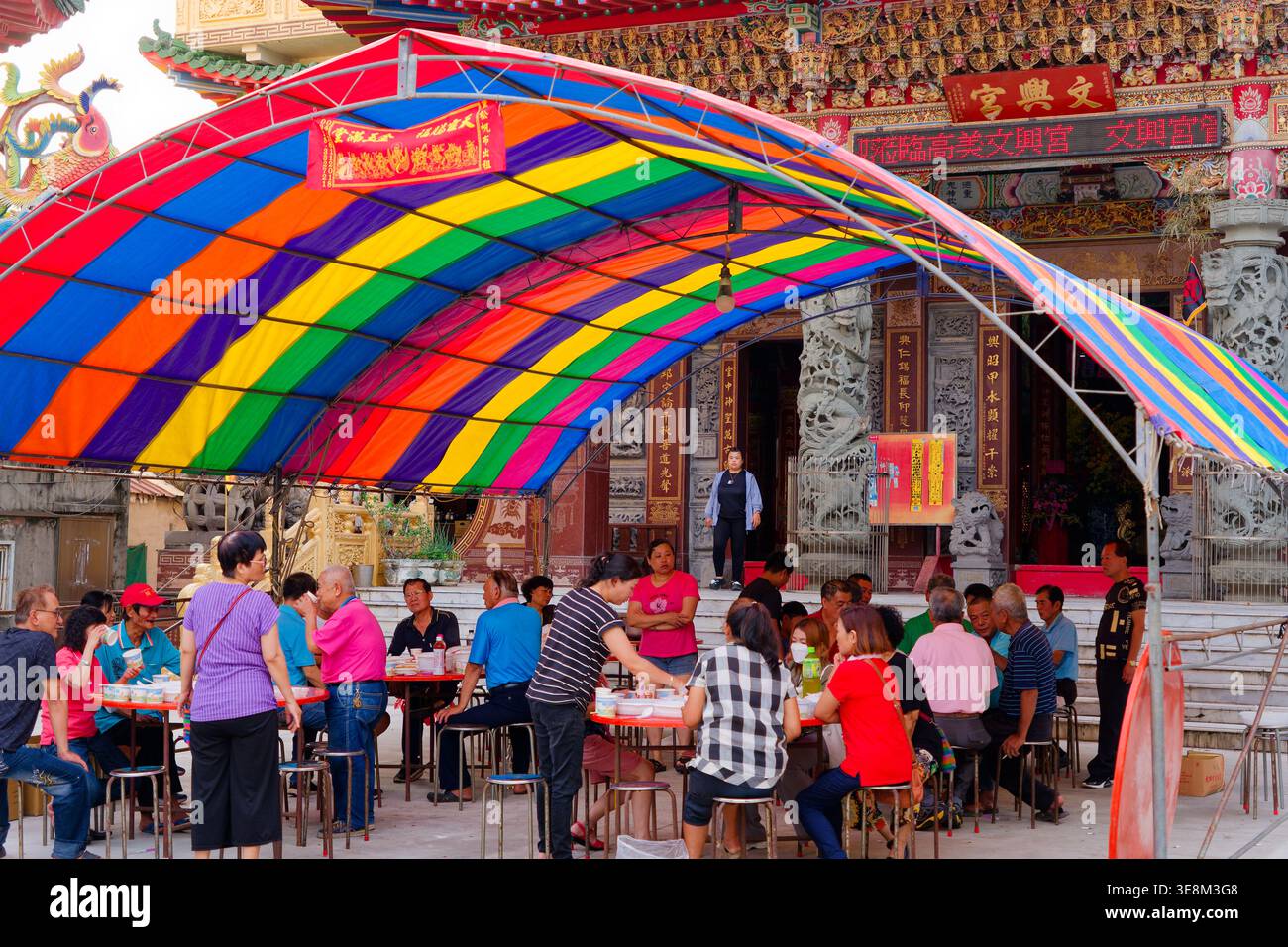 Taichung, Taiwan - 26 mai 2024 : les familles et les dévots partagent des repas abondants sous une canopée arc-en-ciel à l'extérieur du temple Gaomei Wenhsin pendant l'anniversaire de la divinité Banque D'Images