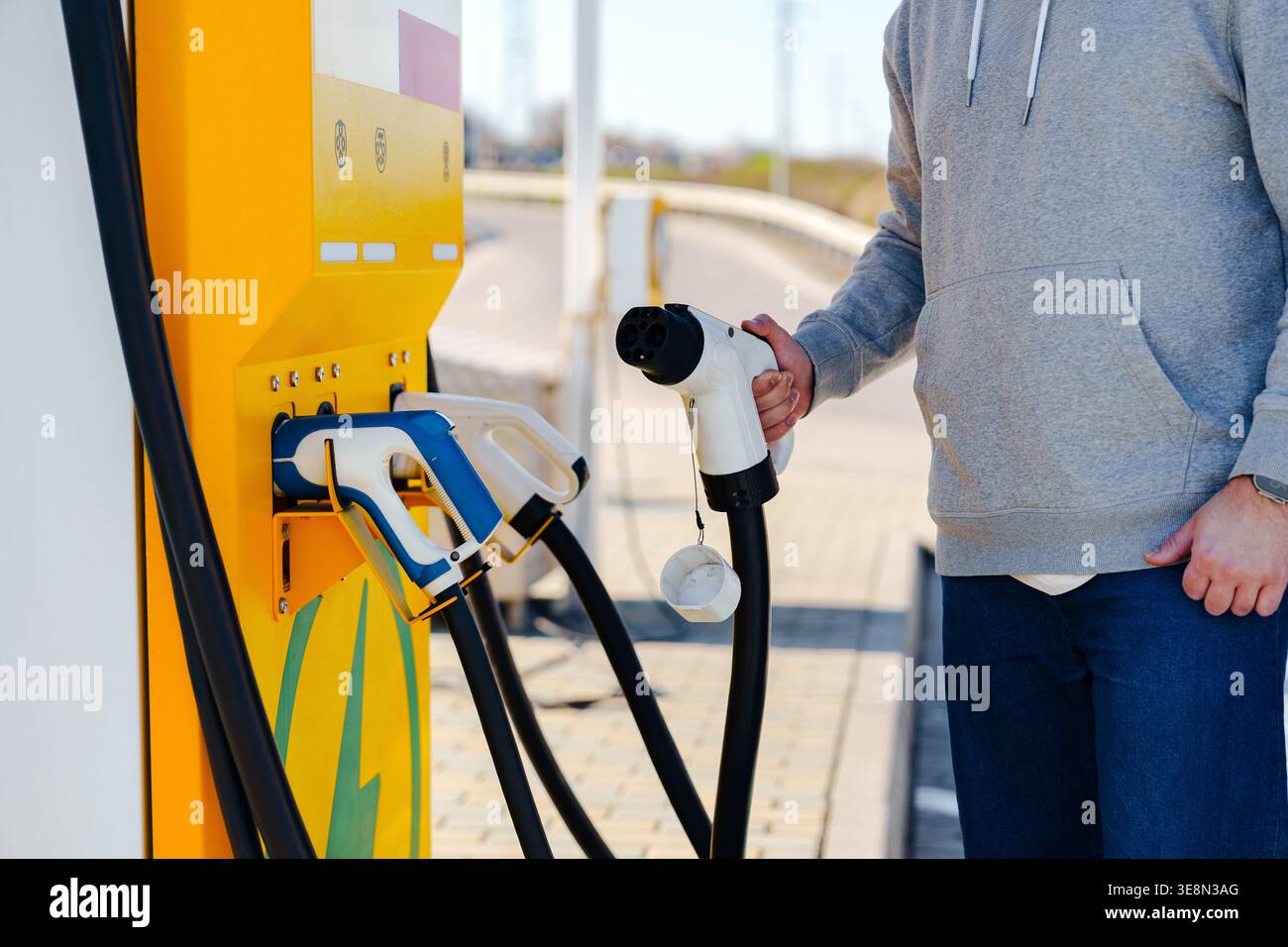 Chargeur de voiture électrique utilisé par une personne à une station de charge en plein jour Banque D'Images