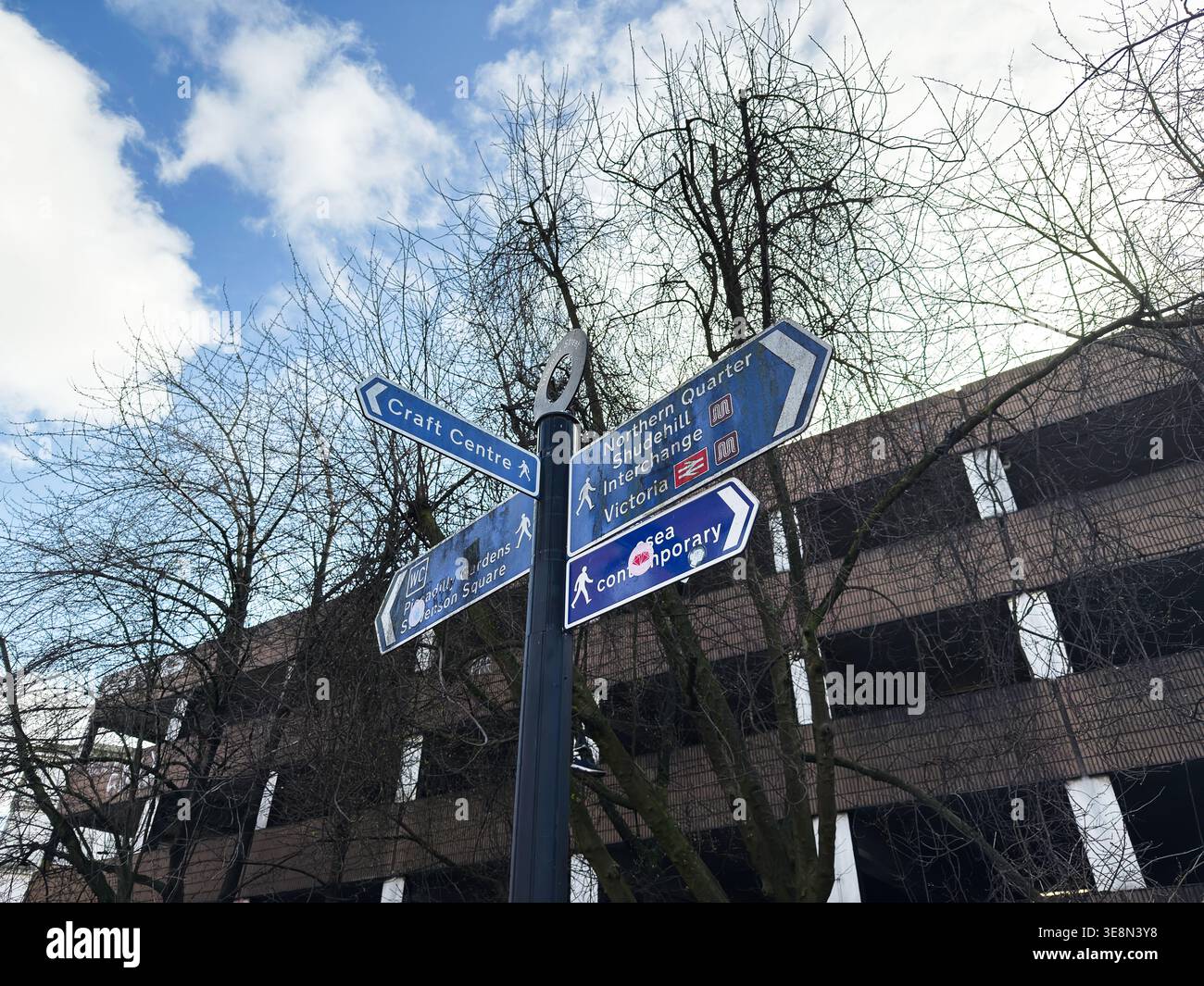 Manchester, Royaume-Uni - 22 février 2026 : panneau de signalisation urbain à Manchester, Royaume-Uni indiquant les attractions culturelles et les routes piétonnes sous ciel nuageux Banque D'Images