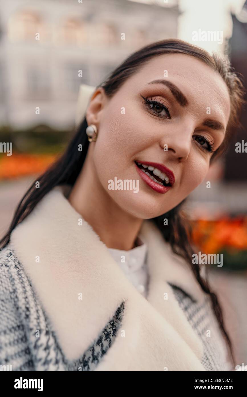 Femme souriant portrait d'une dame élégante portant un manteau en tweed avec col en fausse fourrure blanche à l'extérieur pendant l'heure d'or Banque D'Images