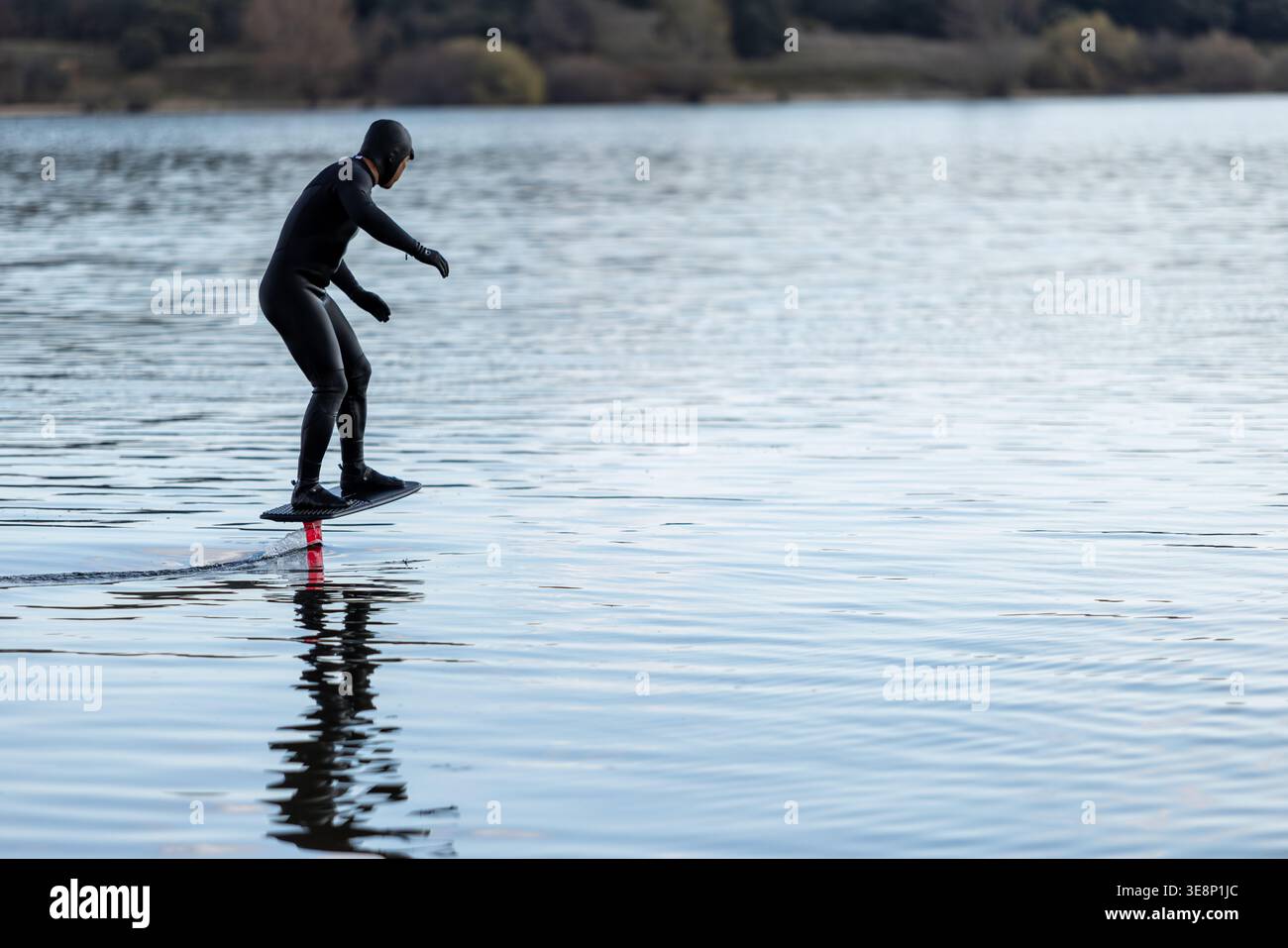 Athlète glissant au-dessus de la surface de l'eau sur une planche d'hydrofoil dans une séance de surf moderne. Banque D'Images