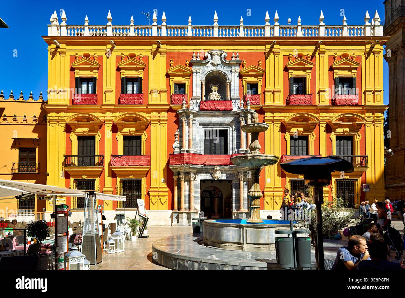 Les touristes se rassemblent autour d'une fontaine dans le centre-ville historique de Malaga. Le soleil brille sur les bâtiments vibrants et l'atmosphère animée. Banque D'Images