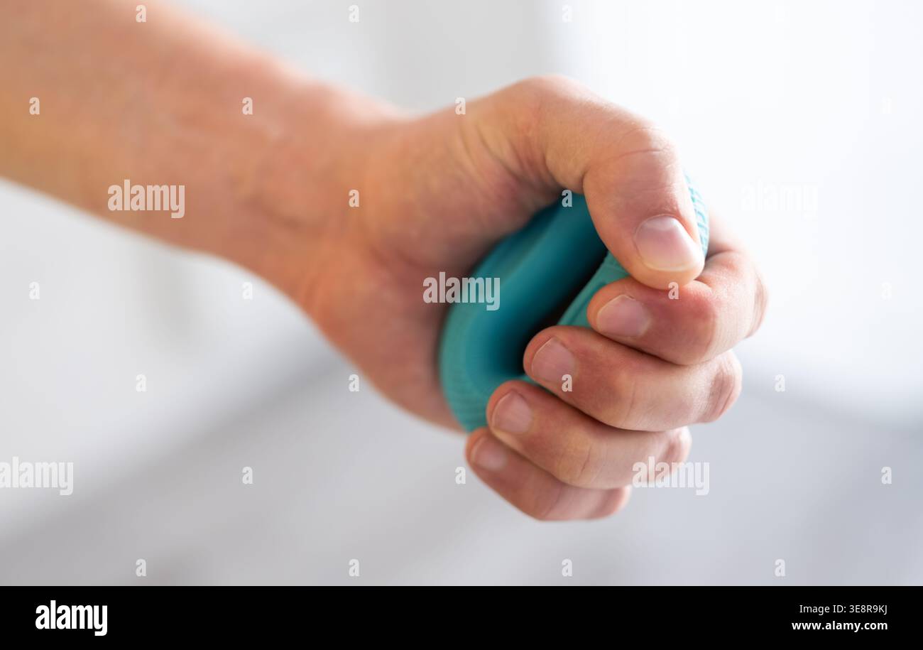 Man Squeezing Hand Grip renforçateur pour la force de l'avant-bras gros plan Banque D'Images