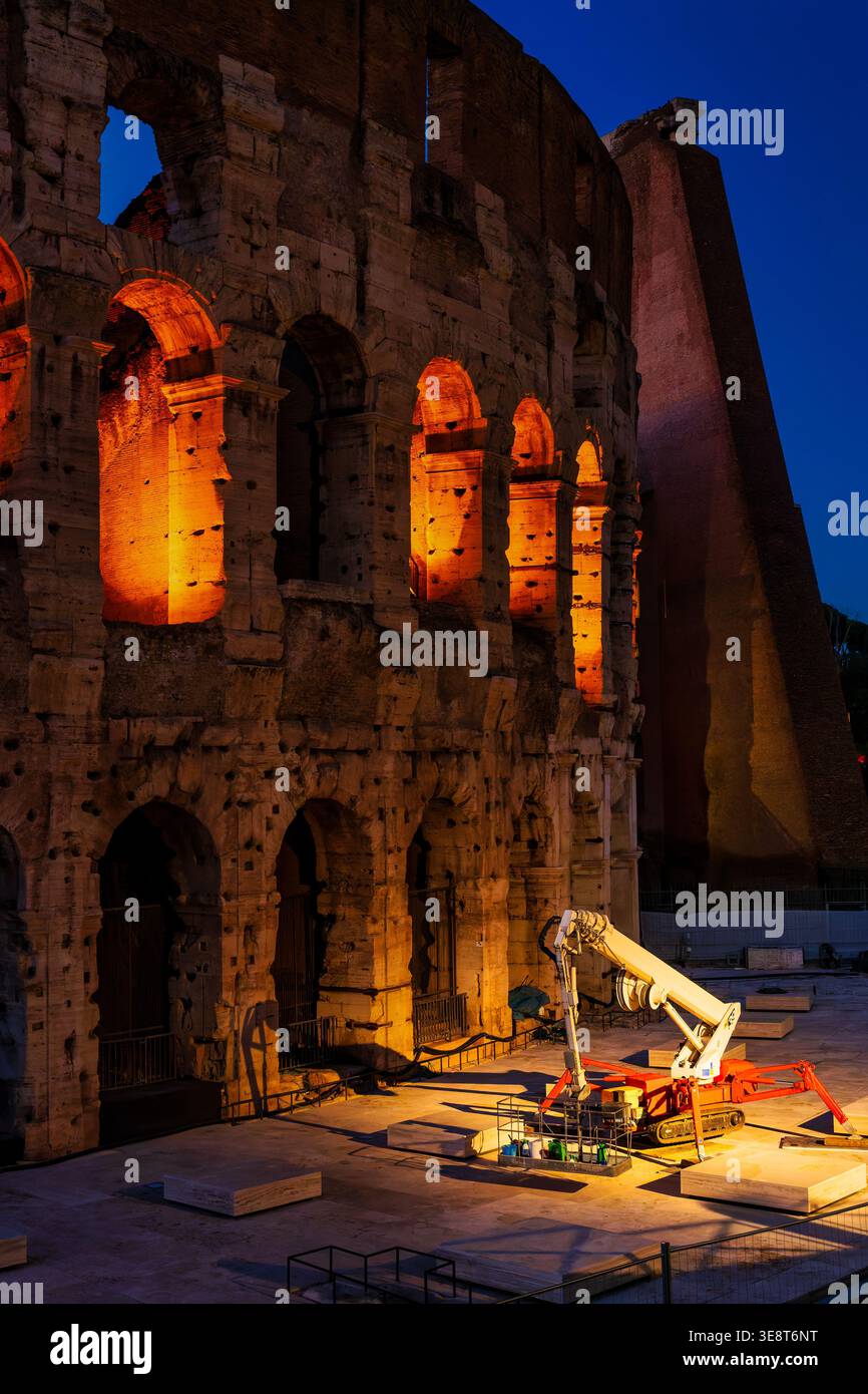 Grue araignée garée sur la façade extérieure illuminée du Colisée à Rome, Latium, Italie, au crépuscule. Banque D'Images