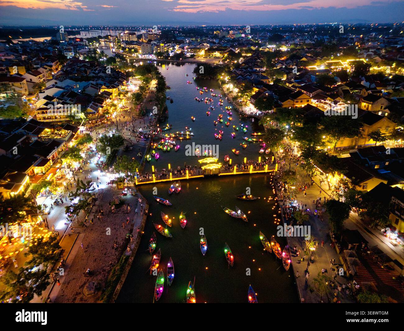 Vue aérienne de la ville antique de Hoi an la nuit avec des bateaux lanternes colorés sur la rivière Thu bon et des bâtiments historiques illuminés à Hoi an, Vietnam. Banque D'Images