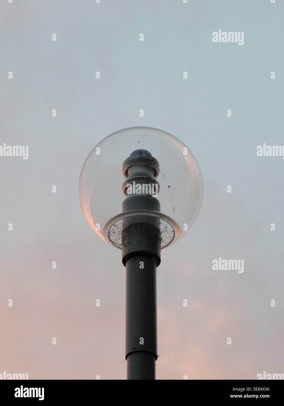 Un lampadaire globe minimaliste le long du remblai du Rhin de Düsseldorf, silhouetté contre un ciel nocturne doux près de la rivière. Banque D'Images