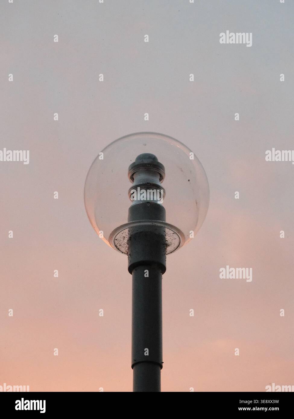 Un lampadaire globe minimaliste le long du remblai du Rhin de Düsseldorf, silhouetté contre un ciel nocturne doux près de la rivière. Banque D'Images