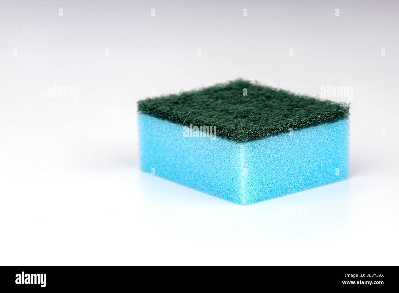 Photographie de produit professionnel d'une éponge de cuisine en mousse bleue avec un tampon abrasif vert sur le dessus, isolé sur fond blanc pour le commerce Banque D'Images