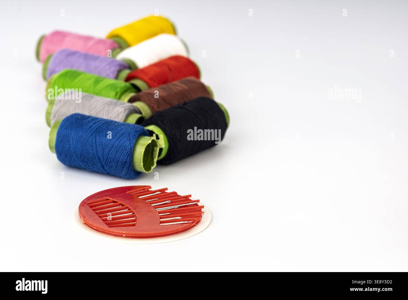 Collection de bobines de fil de broderie vibrantes disposées en diagonale avec des bobines bordées de néon dans plusieurs couleurs, y compris bleu, gris, vert, rose, purp Banque D'Images
