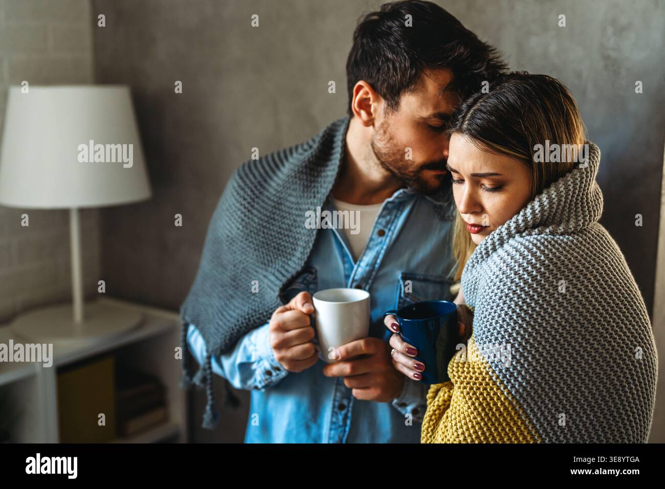 Un couple aimant partage un matin d'hiver tranquille enveloppé dans des couvertures chaudes, trouvant une intimité émotionnelle Banque D'Images