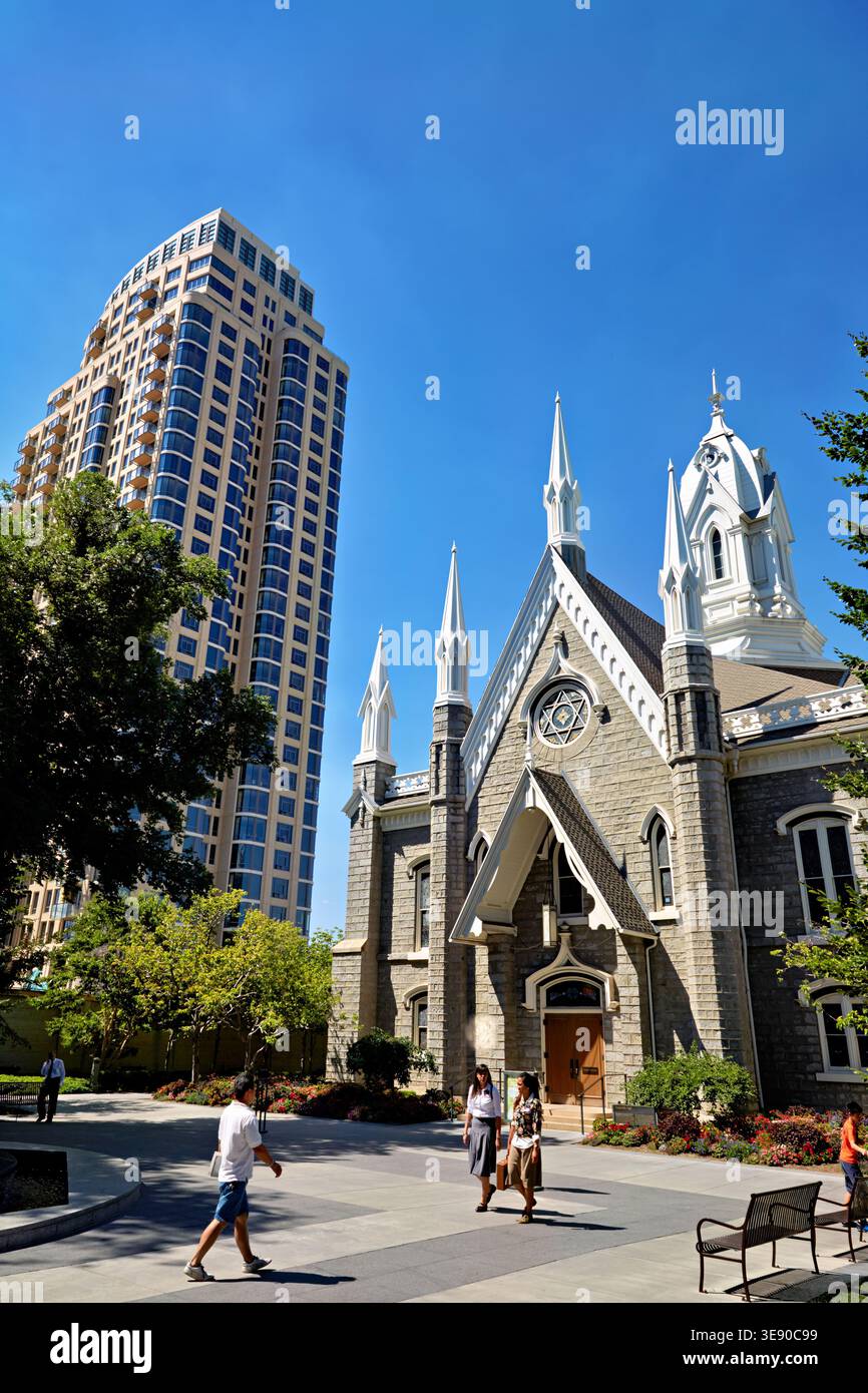 Les gens marchent près de la salle des assemblées à Temple Square. La structure est entourée de bâtiments et d'arbres par une journée ensoleillée. Banque D'Images
