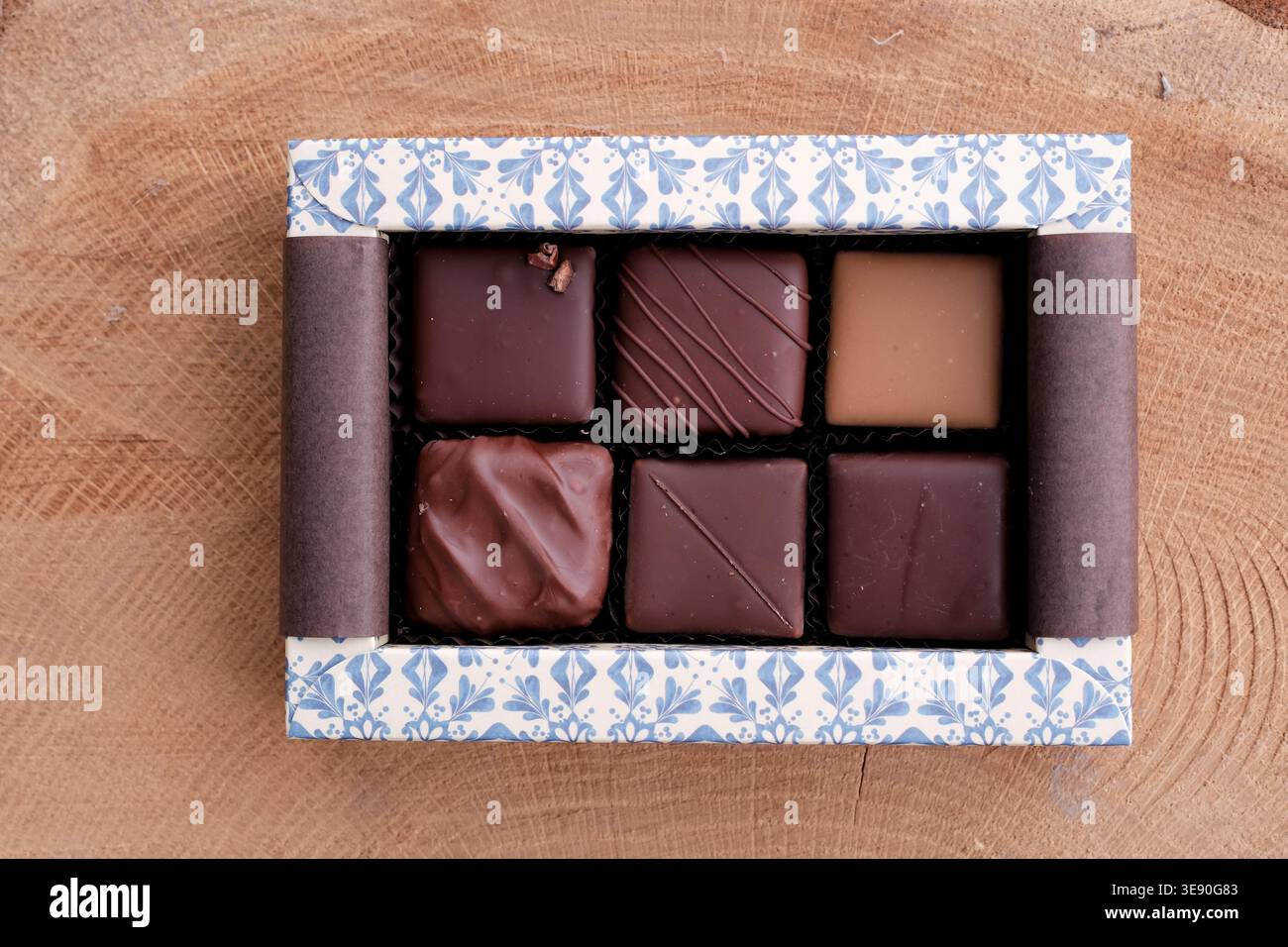 Six pralines dans une boîte sur une surface en bois de chêne. Chocolat artisanal Bean to Bar avec emballage écologique. Assortiment varié de bonbons au praliné au chocolat. Banque D'Images