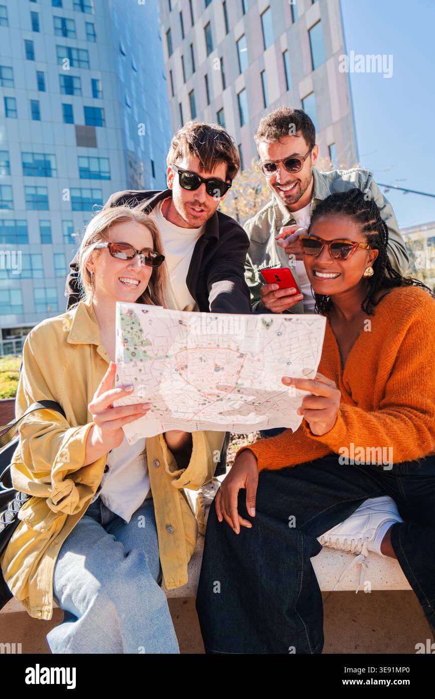 Des amis enthousiastes se sont réunis joyeusement en examinant une carte de la ville, planifiant avec impatience leur prochaine aventure avec excitation et curiosité Banque D'Images