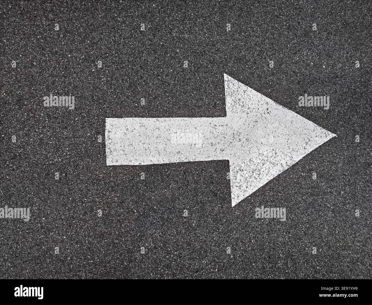 Flèche directionnelle blanche peinte sur la surface d'asphalte foncé. Marquage simple et direct de la direction. Banque D'Images