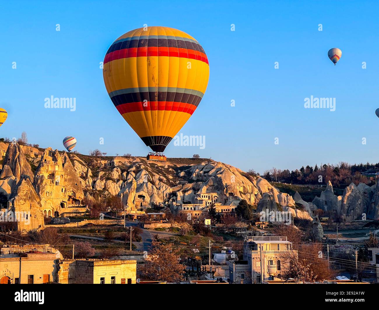 Montgolfières volant au-dessus des cheminées de fées et des maisons de grottes au coucher du soleil, Goreme, Cappadoce, Turquie - Image de stock capturée avec un smartphone