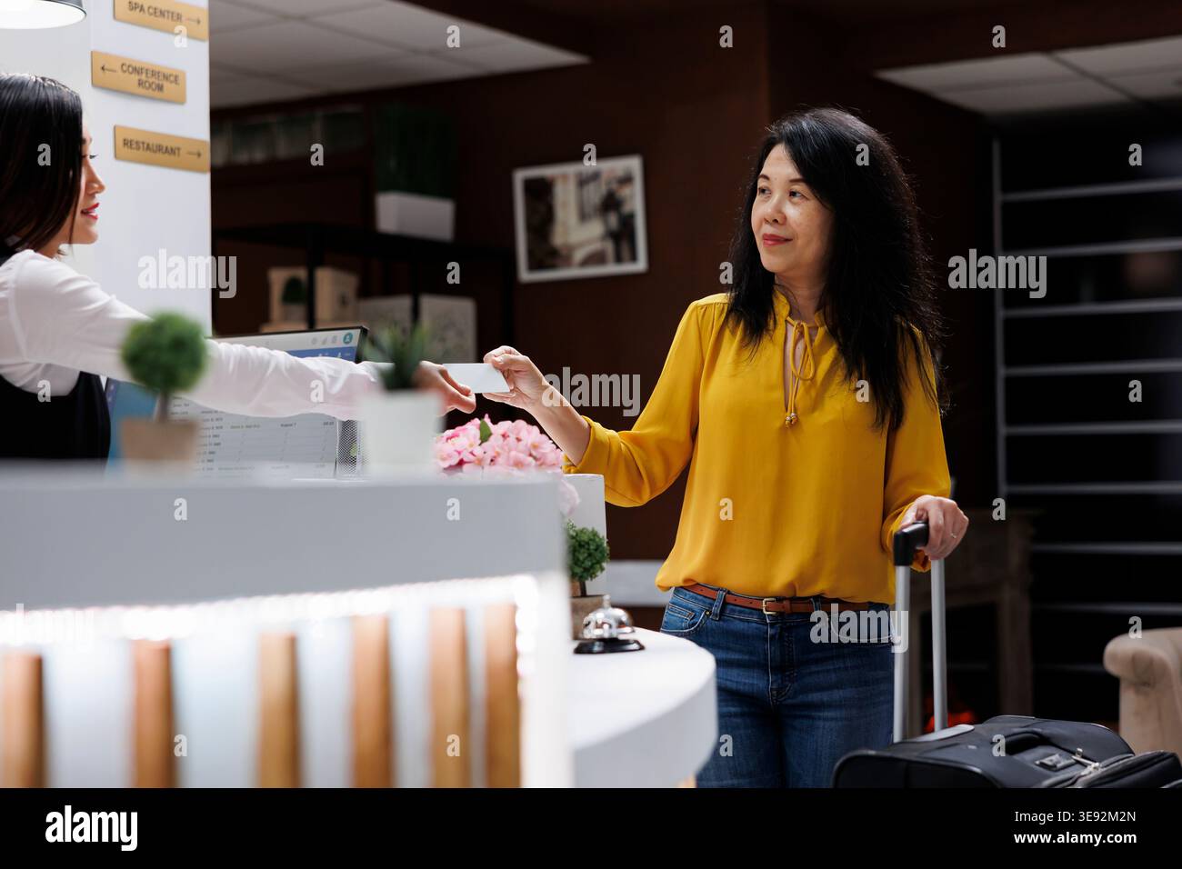 Le préposé à la réception remet la carte-clé asiatique une fois l'enregistrement terminé. Après avoir terminé le processus de réservation pour l'hôtel agréable, le client est prêt à aller à l'hébergement. Banque D'Images