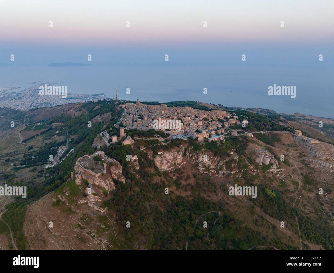 Vue aérienne de la ville historique perchée sur une colline d'Erice perchée sur une falaise rocheuse avec des bâtiments en pierre et la côte méditerranéenne en arrière-plan Erice, S. Banque D'Images