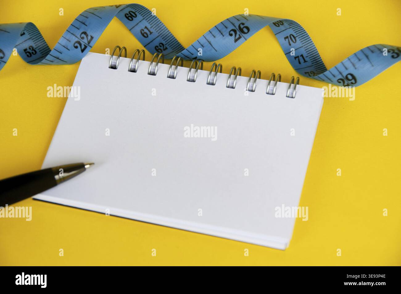 Ruban de mesure diététique avec cahier vierge sur couverture jaune Banque D'Images