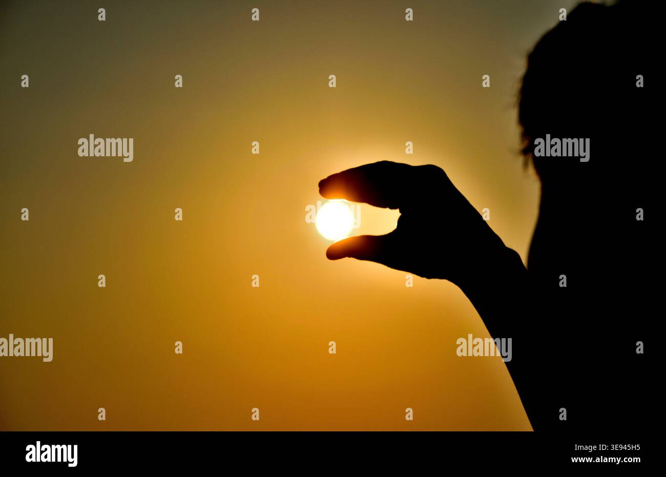 Homme tenant le soleil entre les doigts – chaleur extrême, changement climatique et concept de réchauffement planétaire Banque D'Images