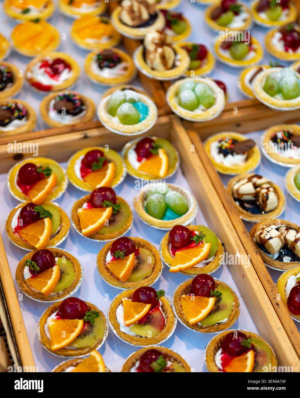 Tasses à dessert assorties avec des fruits et du chocolat affichés sur le marché étal, sélection sucrée colorée avec raisins kiwi orange et mangue, prêt à la vente i Banque D'Images