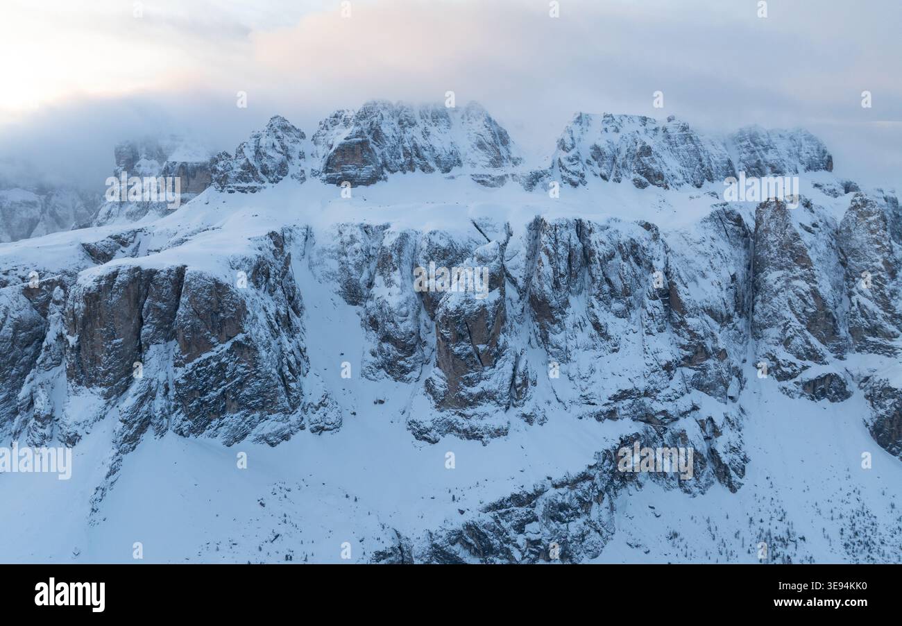 Vue aérienne des sommets enneigés des Dolomites partiellement couverts par les nuages et la brume pendant l'hiver à Selva di Val Gardena, Trentin-Haut-Adige, Banque D'Images