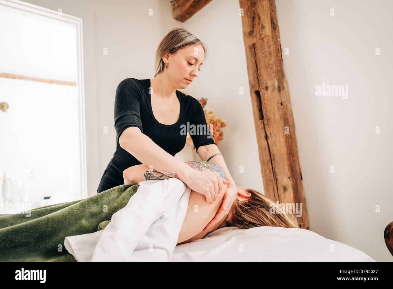 Thérapeute effectuant des massages du cou et des épaules dans la salle spa sereine Banque D'Images