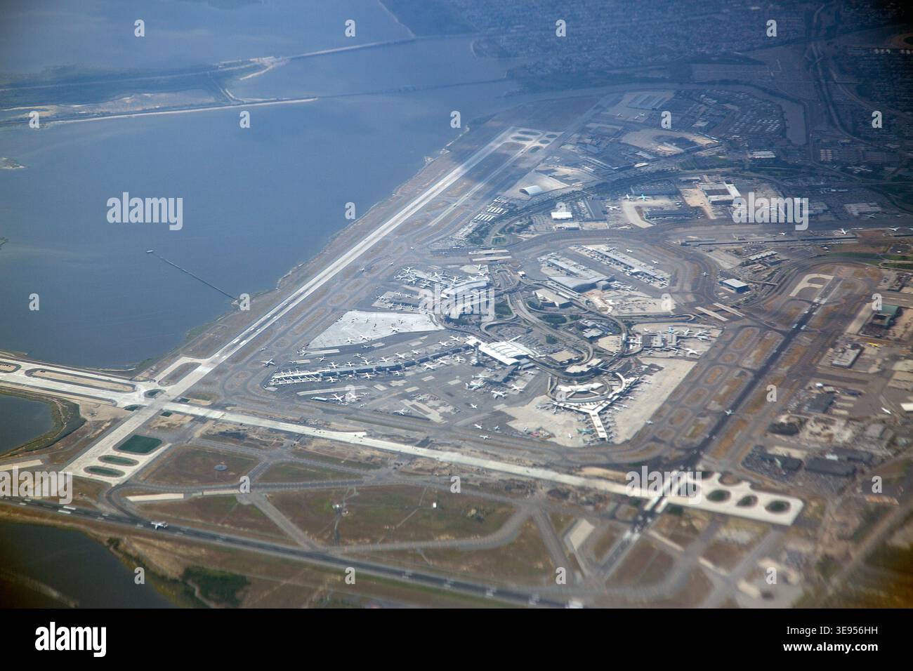 Vue aérienne d'un complexe aéroportuaire avec pistes, terminaux et voies de circulation adjacentes à une grande étendue d'eau. Banque D'Images