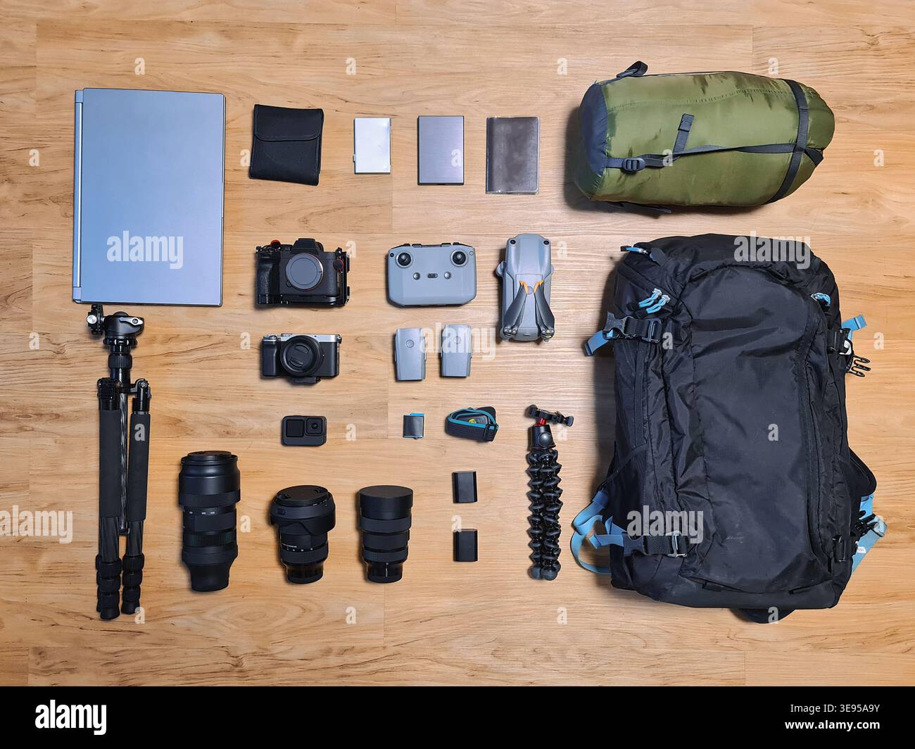Organisation de matériel de photographe professionnel avec appareil photo, objectif, sac à dos, ordinateur portable, étui, filtre, trépied, drone et sac de couchage sur plancher en bois. Prepa Banque D'Images
