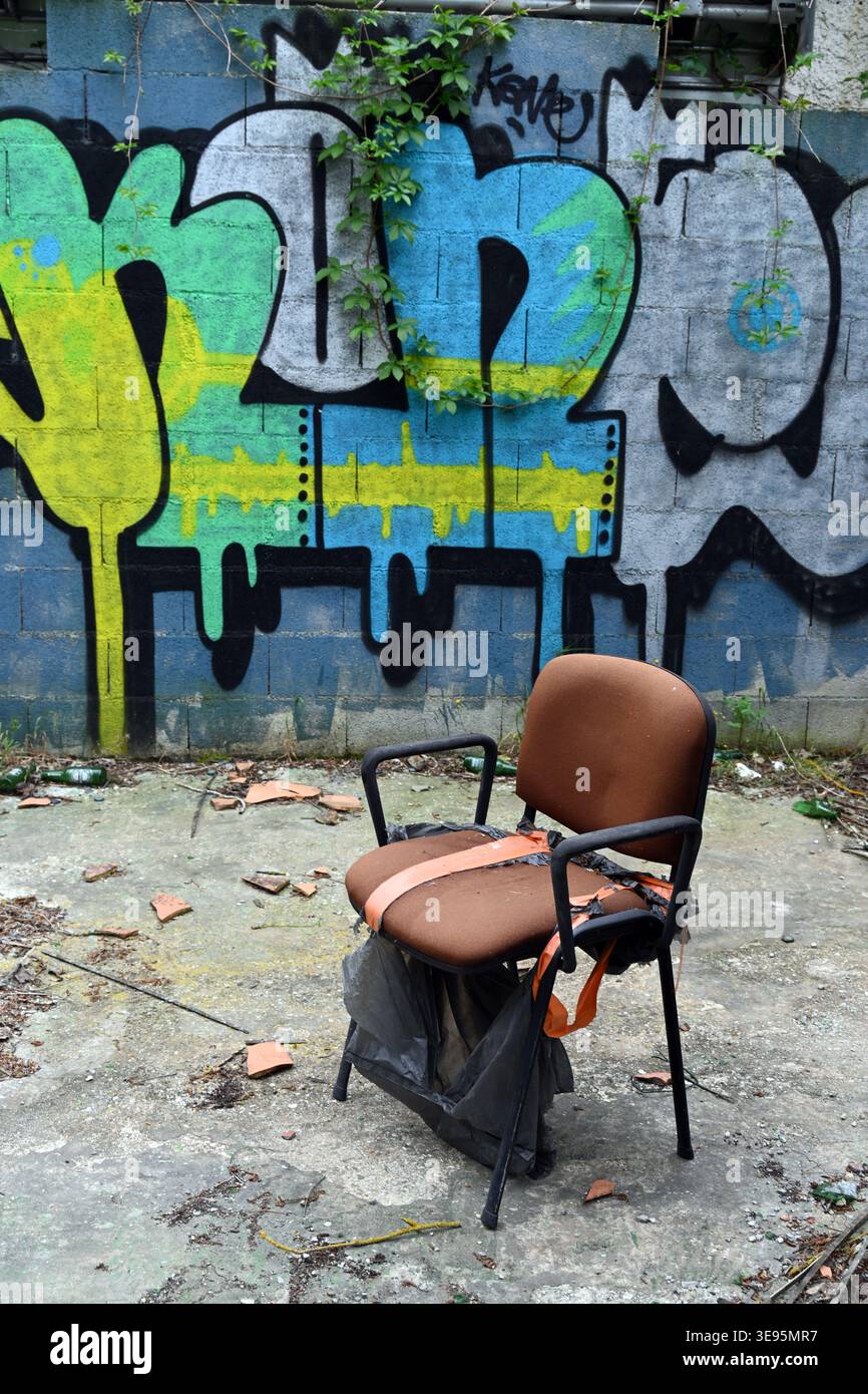 Chaise abandonnée ou fauteuil et mur couvert de gaffiti Banque D'Images