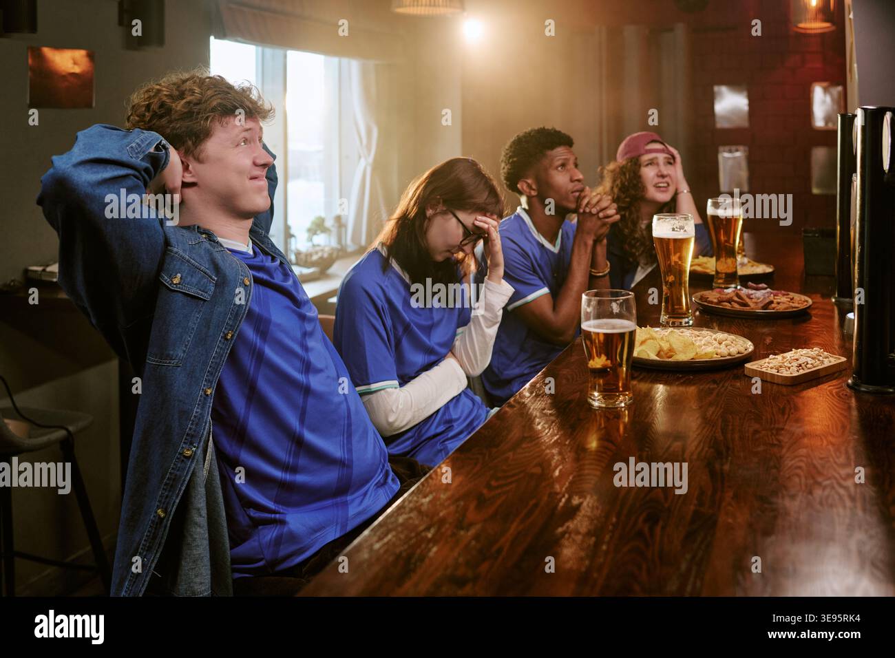 Amis divers regardant le sport au bar et réagissant au match Banque D'Images