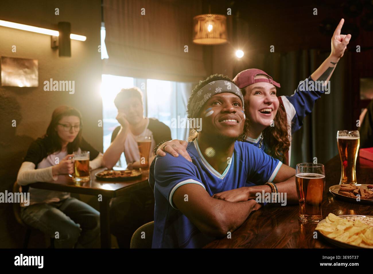 Amis multiethniques regardant le sport au bar et célébrant la victoire Banque D'Images